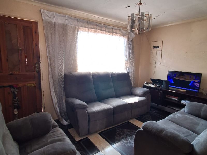 A living room featuring tiled flooring and a central light fixture, requiring cosmetic updates to the ceiling and door finishes.
