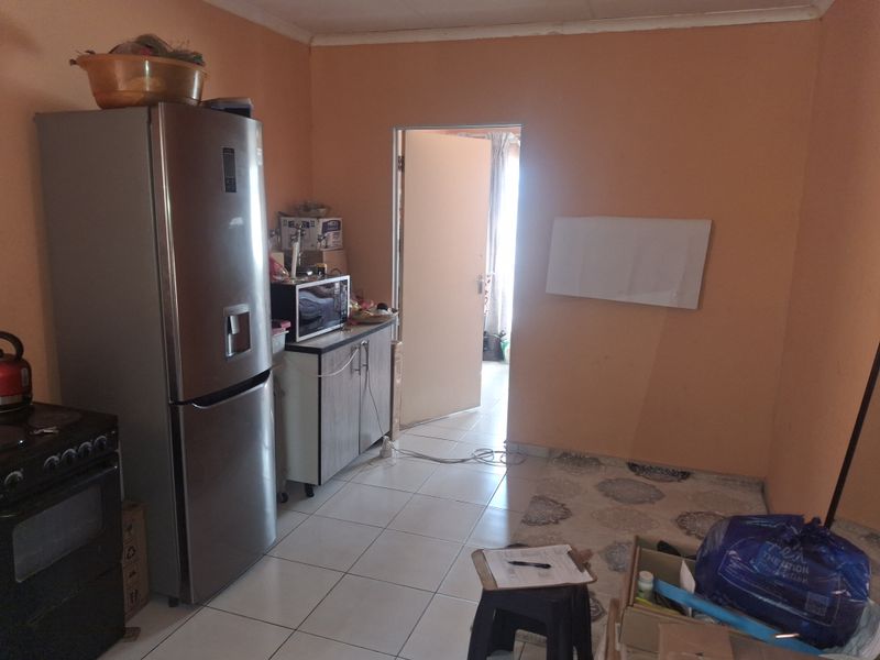 A functional kitchen area featuring tiled flooring, built-in cabinetry, and a stove, requiring cosmetic updates to improve the overall aesthetic and condition.