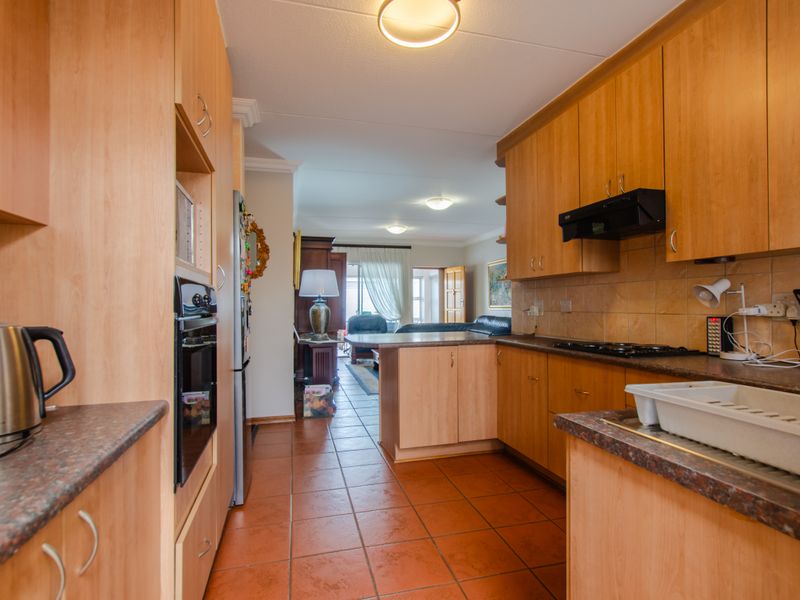Open plan kitchen featuring laminate cabinetry and countertops, flowing into the living area with tiled flooring throughout.