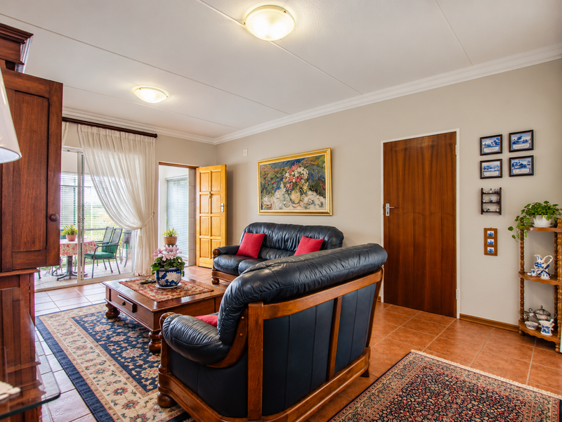 A well-maintained living room featuring tiled flooring, coved ceilings, and direct access to an outdoor patio through sliding glass doors.