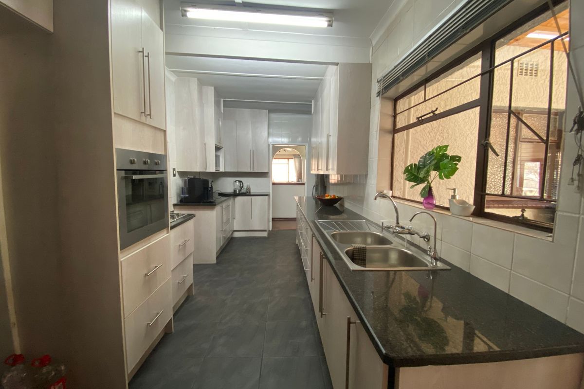 A functional kitchen featuring light-toned cabinetry, dark granite countertops, a double sink, and a built-in oven with ample storage space.