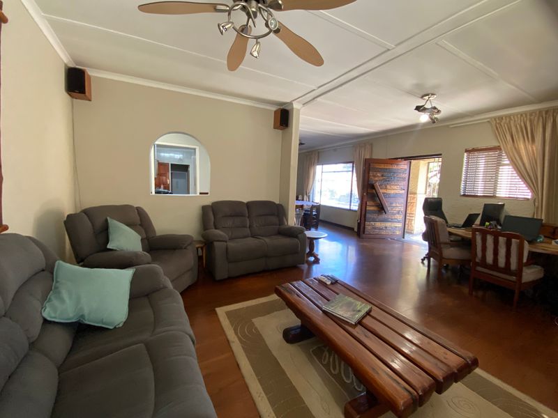 Spacious open-plan living area featuring wooden flooring, a ceiling fan, and an arched pass-through window connecting to the kitchen.