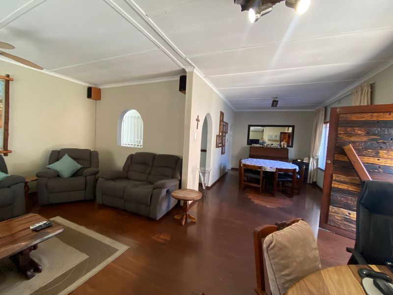 Open plan living and dining area featuring timber flooring, arched architectural details, and ceiling fan lighting.