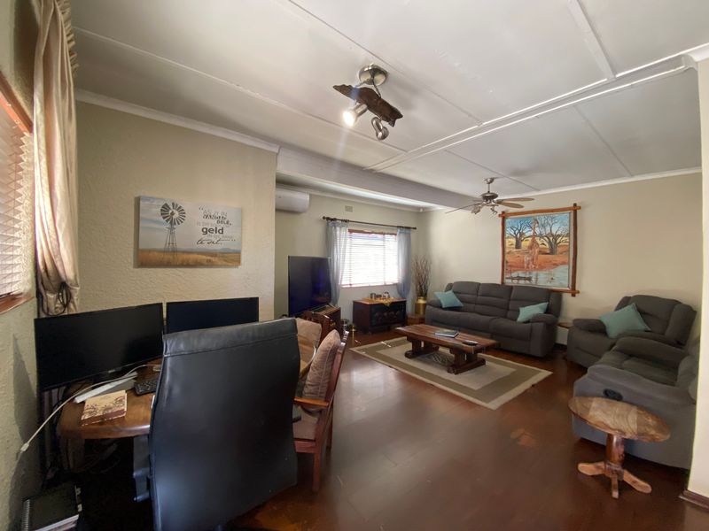 Spacious living room featuring timber flooring, ceiling fan, and split-system air conditioning, offering a comfortable and functional layout for relaxation and home office use.
