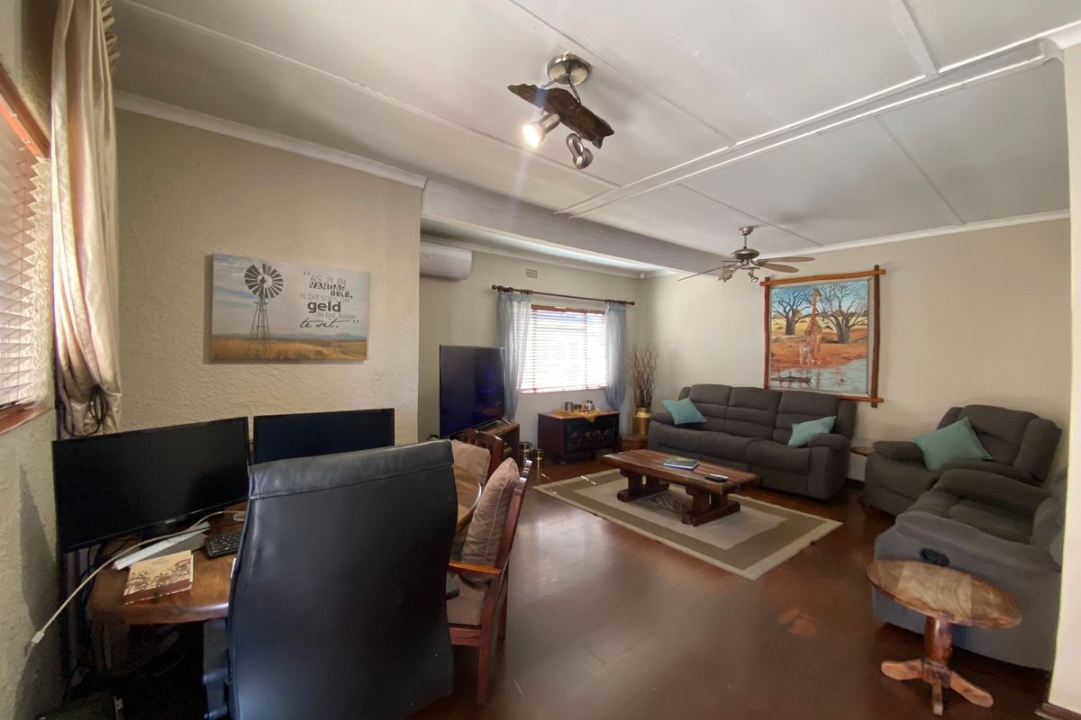 Spacious living room featuring timber flooring, ceiling fan, and split-system air conditioning, offering a comfortable and functional layout for relaxation and home office use.