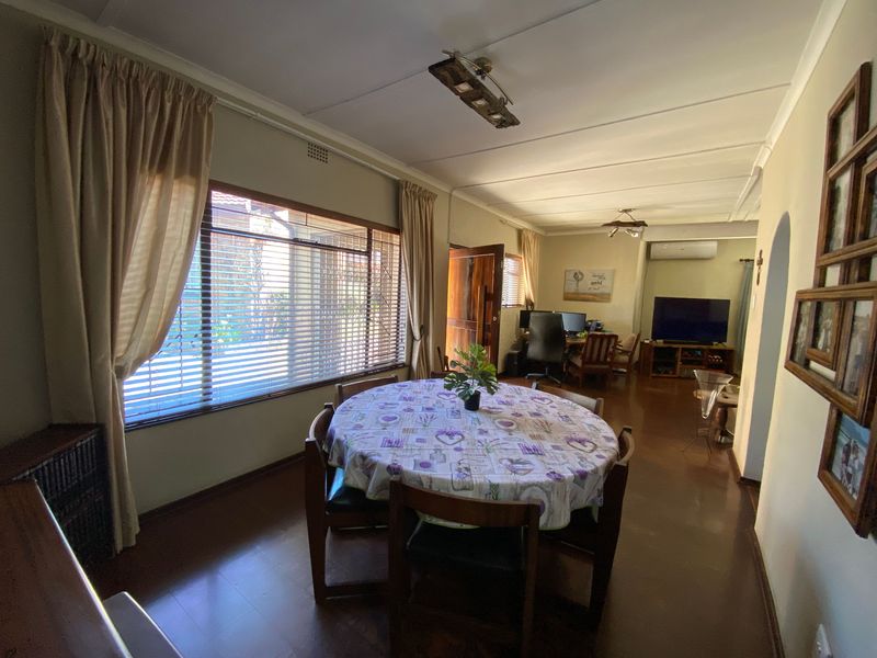 Open plan living and dining area featuring large windows, laminate flooring, and an integrated air conditioning unit.