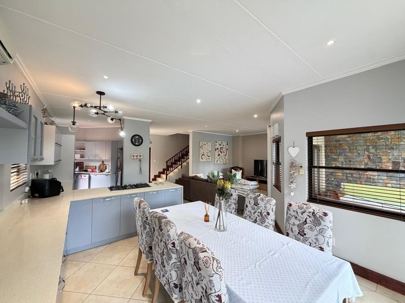 Spacious open-plan living area featuring a modern kitchen with stone countertops, gas hob, and a seamless flow to the dining and lounge spaces.