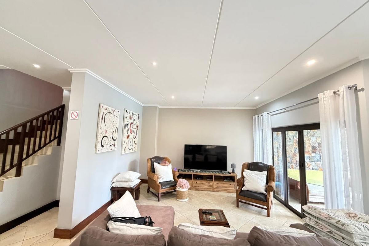 Spacious living room featuring tiled flooring, recessed lighting, and large sliding glass doors providing access to the outdoor area.
