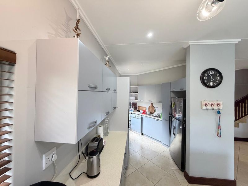 A functional kitchen featuring light-toned built-in cabinetry, stone countertops, tiled flooring, and recessed lighting, offering a clean and practical workspace.