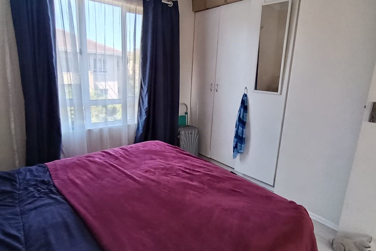A bedroom featuring tiled flooring and a built-in wardrobe with a mirror panel, providing functional storage space.