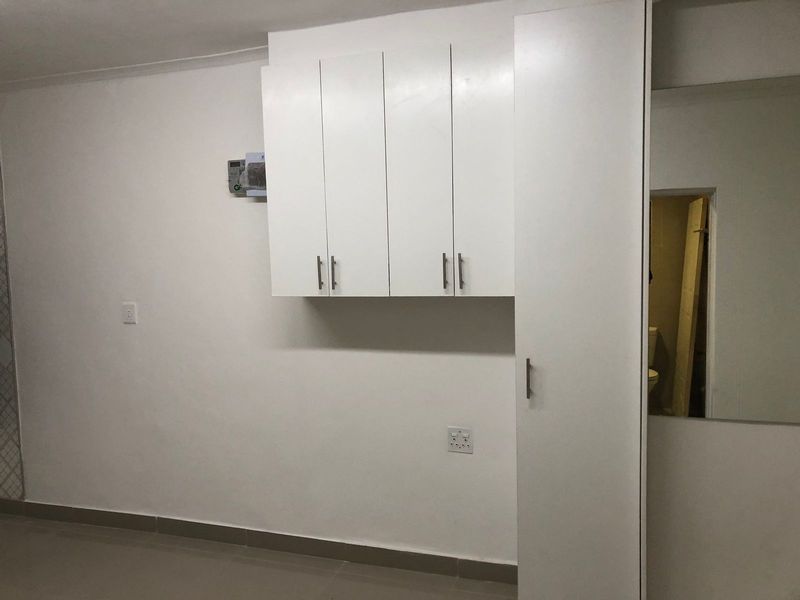 A clean utility space featuring white built-in cabinetry, a tall storage cupboard, and tiled flooring, offering practical storage solutions.