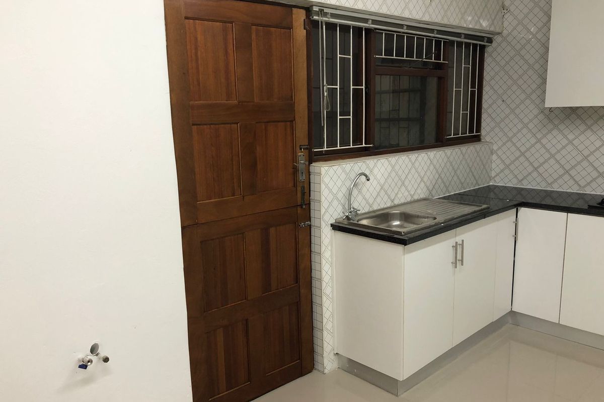 A functional kitchen area featuring white cabinetry, a stone countertop, stainless steel sink, and a traditional timber stable door.