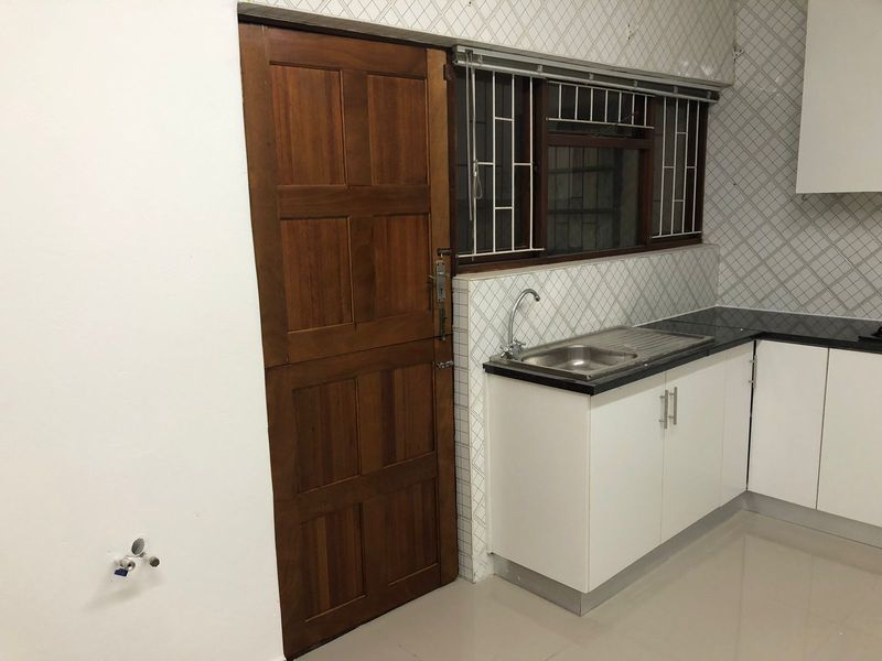 A functional kitchen area featuring white cabinetry, a stone countertop, stainless steel sink, and a traditional timber stable door.