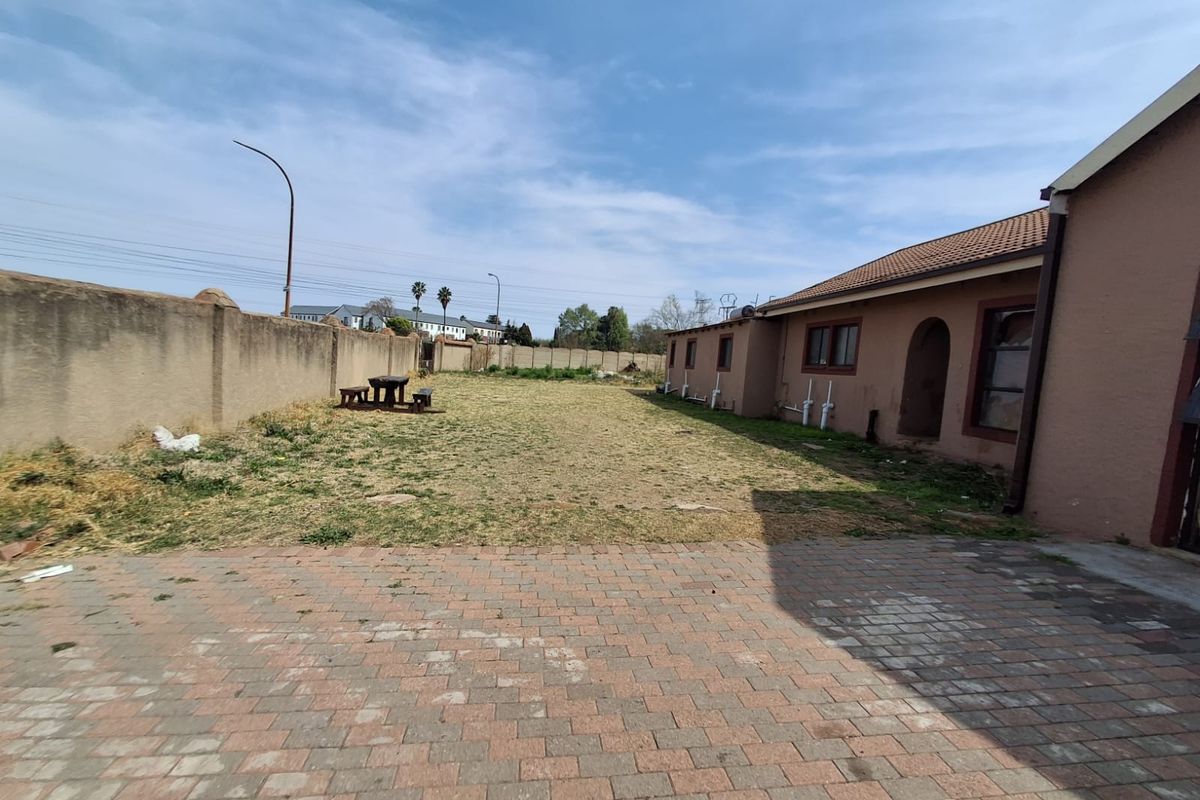 Spacious rear yard featuring a paved patio area, perimeter walling, and a large lawn, offering significant potential for landscaping and outdoor living improvements.