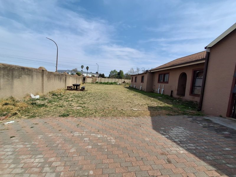 Spacious rear yard featuring a paved patio area, perimeter walling, and a large lawn, offering significant potential for landscaping and outdoor living improvements.