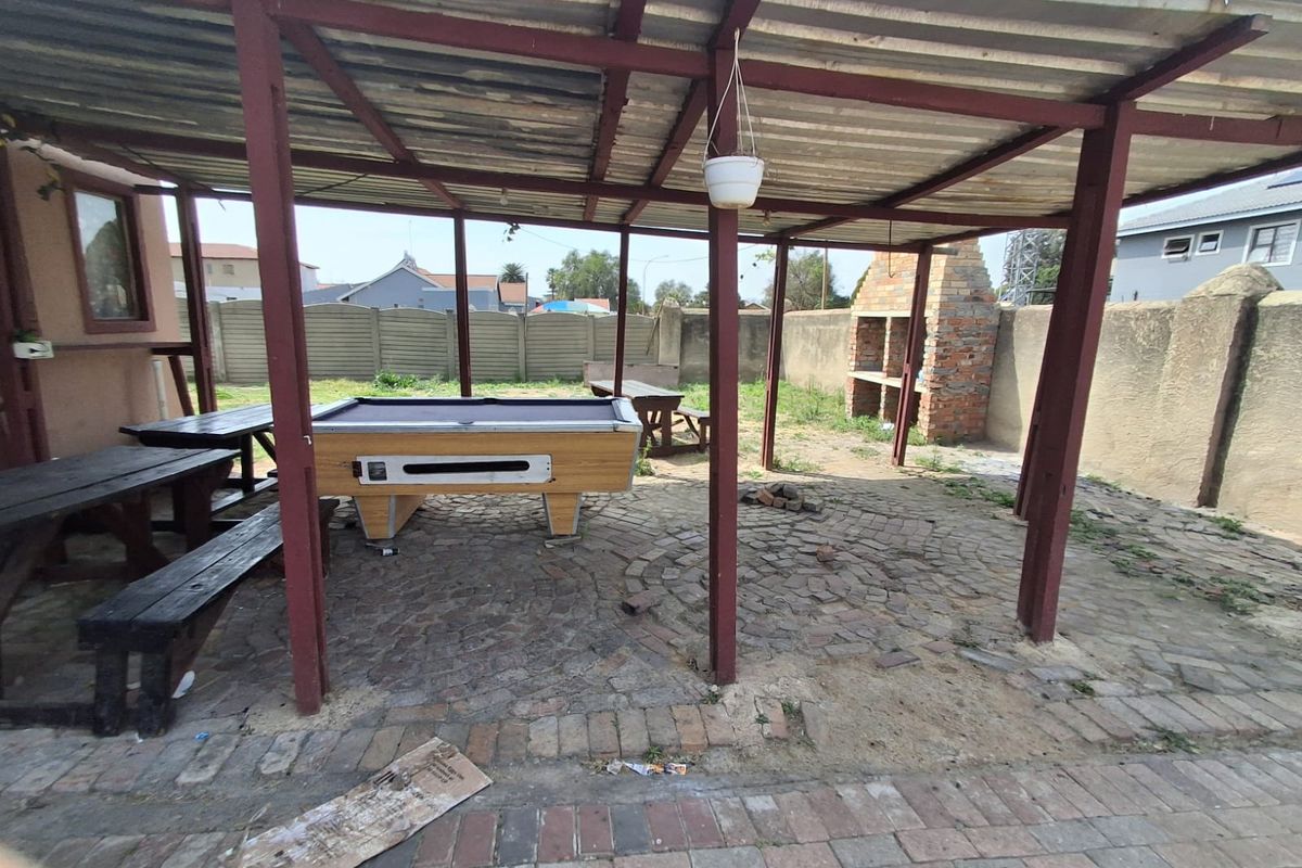 Covered outdoor patio area featuring a built-in brick braai and paved flooring, providing a functional space for outdoor entertainment.