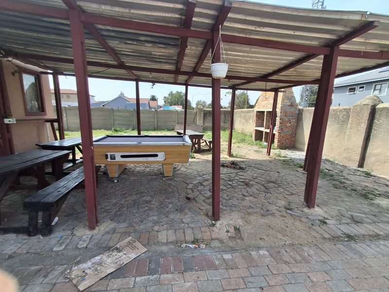 Covered outdoor patio area featuring a built-in brick braai and paved flooring, providing a functional space for outdoor entertainment.