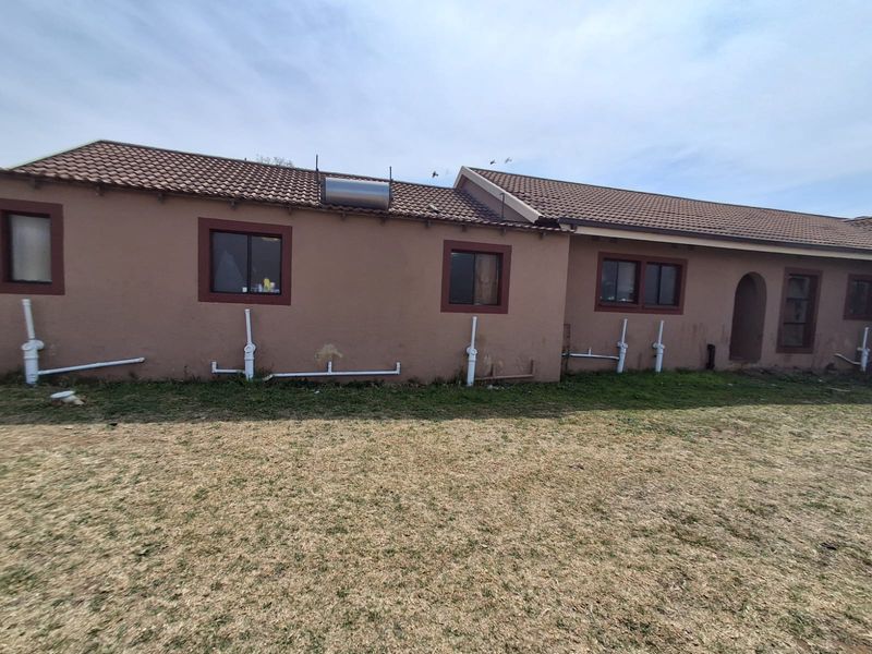 Rear exterior view of the house featuring a tiled roof, solar water heater, and exposed external plumbing pipes along the wall.