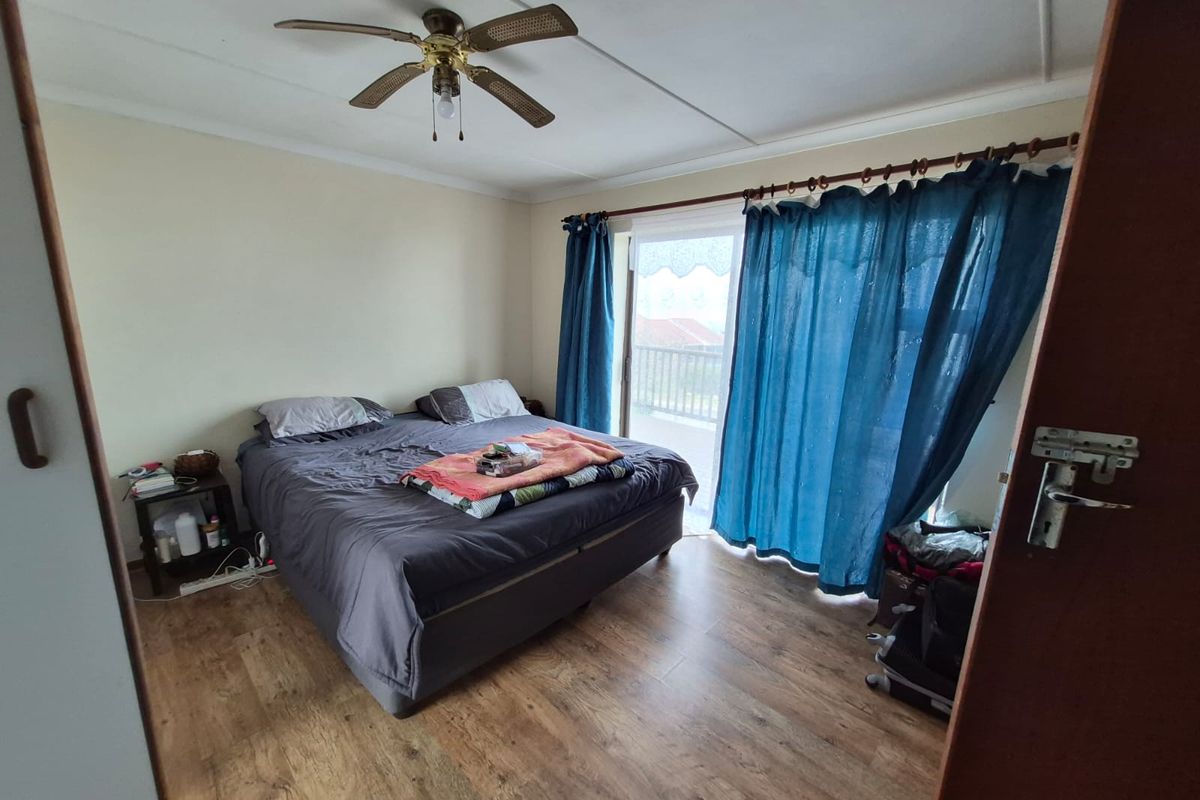 A bedroom featuring laminate flooring, a ceiling fan, and a sliding glass door providing access to an outdoor area.