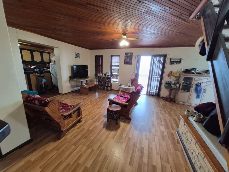Spacious living area featuring a vaulted timber-clad ceiling, laminate flooring, and direct access to the outdoor area through a sliding glass door.