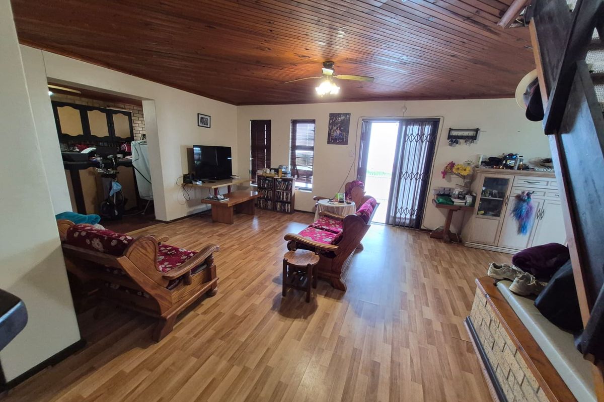 Spacious living area featuring a vaulted timber-clad ceiling, laminate flooring, and direct access to the outdoor area through a sliding glass door.