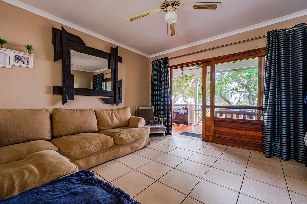 A living room featuring tiled flooring, a ceiling fan, and a large sliding glass door providing access to an outdoor patio area.