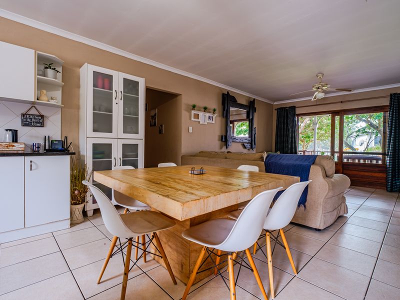 Open-plan living and dining area featuring tiled floors, built-in kitchen cabinetry, and a sliding glass door leading to an outdoor space.