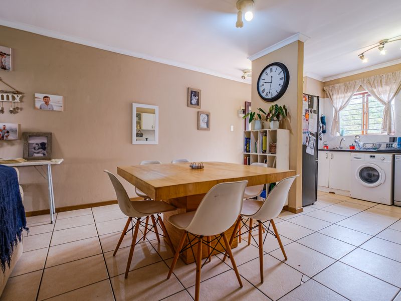 Open plan living and dining area featuring tiled floors and an adjoining kitchen with built-in cabinetry and laundry appliance connections.