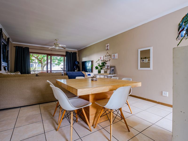 Open-plan living and dining area featuring tiled flooring, a ceiling fan, and large sliding glass doors leading to an outdoor space.