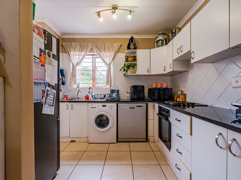 Functional kitchen featuring white cabinetry, dark laminate countertops, tiled backsplash, and integrated appliances including an oven and hob.