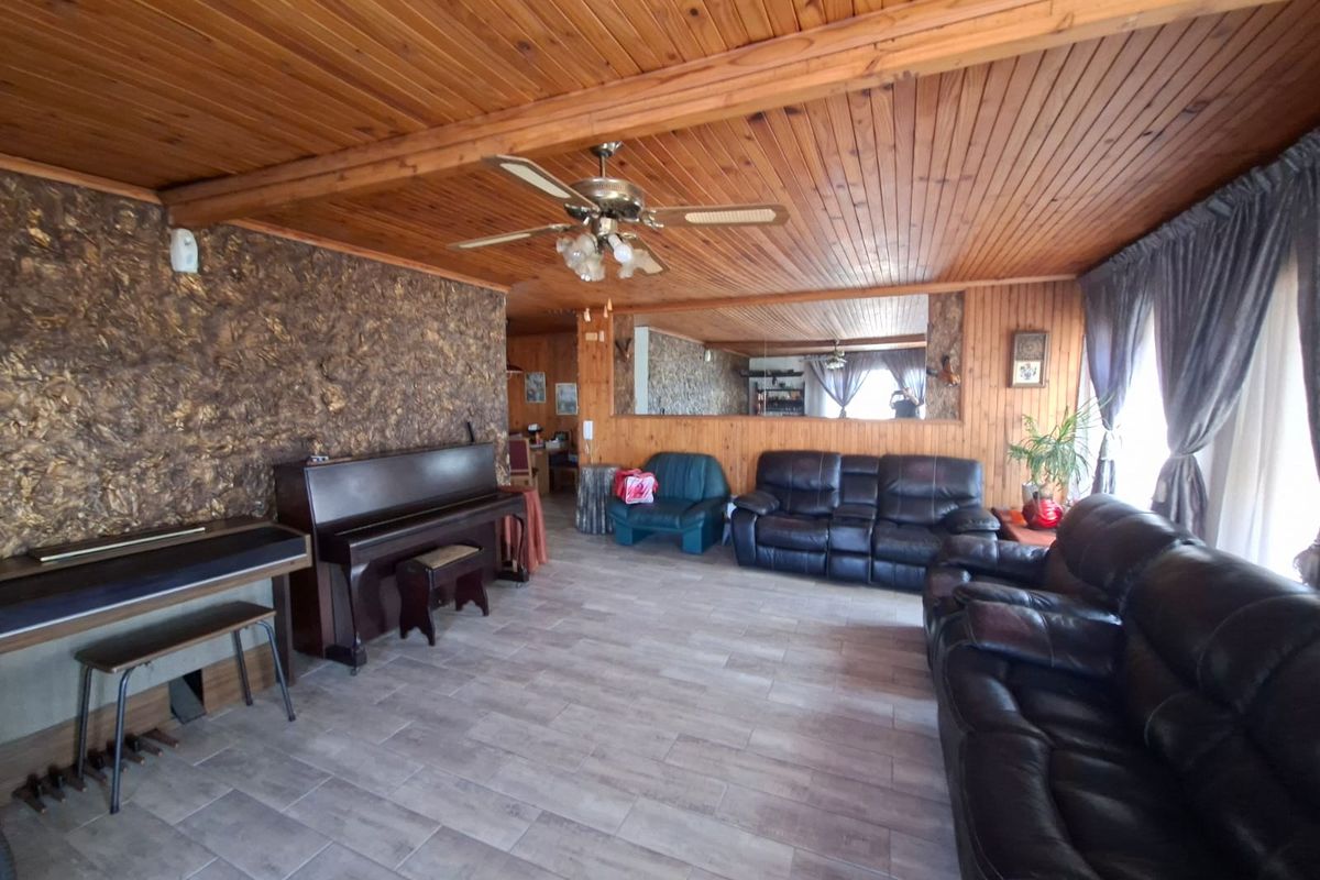 Spacious living room featuring a timber-clad ceiling, tiled flooring, and a textured feature wall, offering a warm and traditional aesthetic.