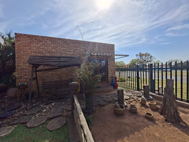 Front exterior view of a face brick house featuring a security gate, paved walkway, and metal perimeter fencing.