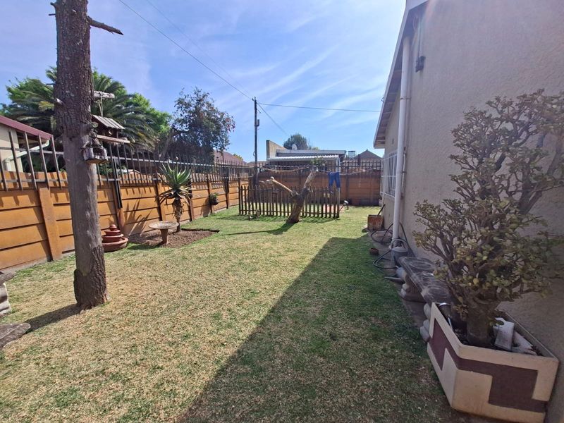 A private rear garden featuring a lawn area enclosed by precast concrete boundary walls and security fencing.