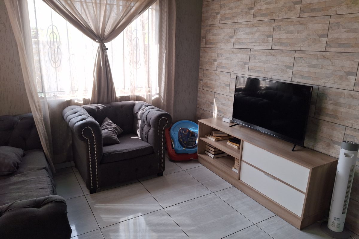 A living room featuring tiled flooring and a textured stone-look feature wall, providing a neutral base for interior design.