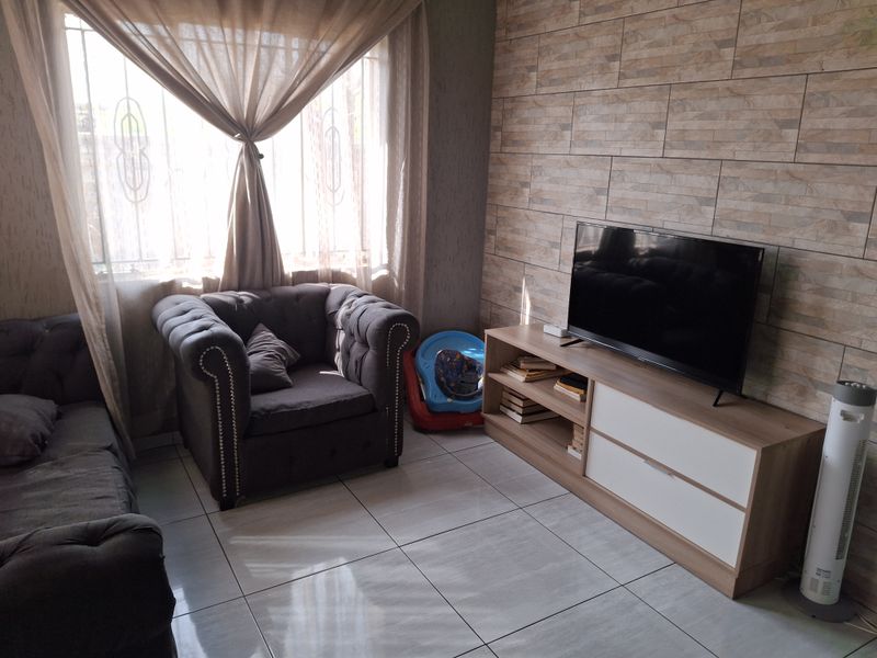 A living room featuring tiled flooring and a textured stone-look feature wall, providing a neutral base for interior design.