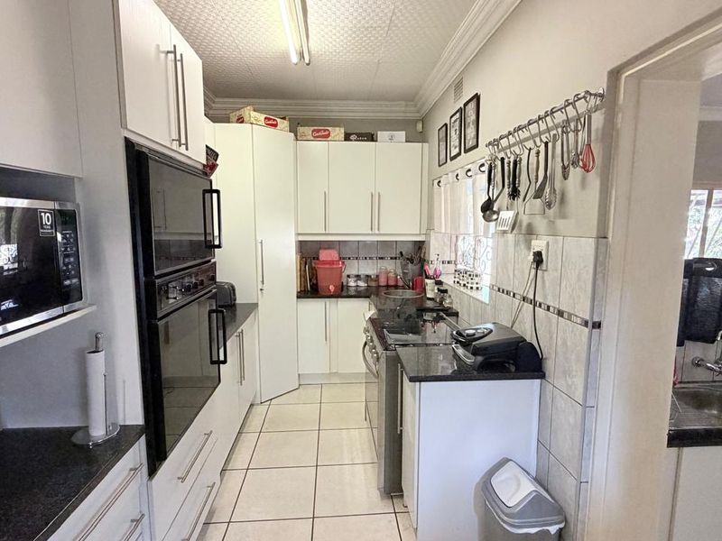 Functional kitchen featuring white cabinetry, granite countertops, built-in oven and microwave, tiled backsplash, and ceramic tile flooring.