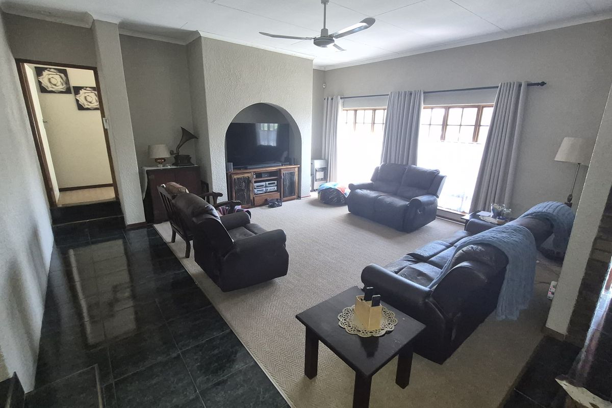 Spacious living room featuring an arched alcove for media storage, ceiling fan, and a combination of tiled and carpeted flooring.