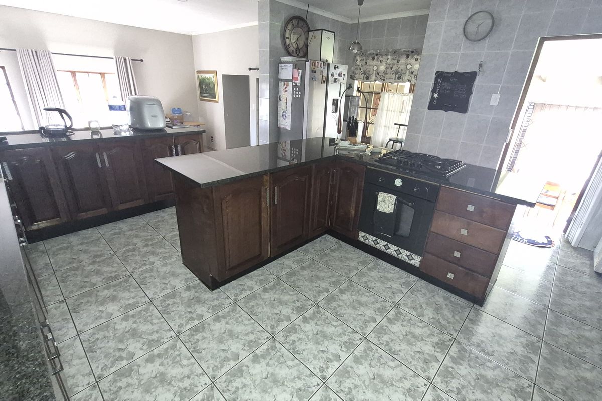 A functional kitchen featuring dark wood cabinetry, granite countertops, a gas hob, and a built-in oven with tiled flooring and splashbacks.