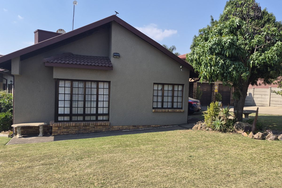 A view of the rear exterior of the house featuring a textured facade, tiled roof, and lattice windows overlooking a lawn.