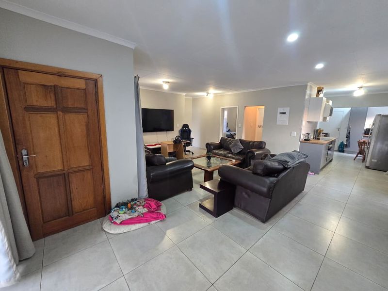 Open-plan living area featuring tiled flooring, recessed lighting, and a connected kitchen space with built-in cabinetry.