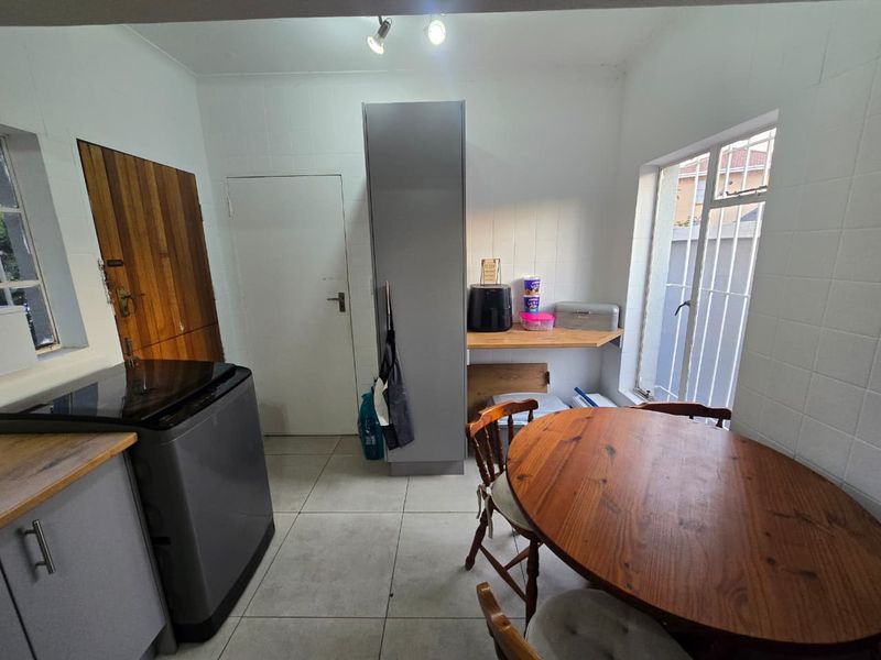A functional kitchen area featuring tiled walls, built-in cabinetry, and a timber countertop, providing a practical space for meal preparation and dining.