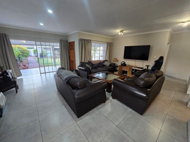 Spacious living room featuring large format floor tiles, recessed lighting, and sliding glass doors providing direct access to the rear patio and garden.