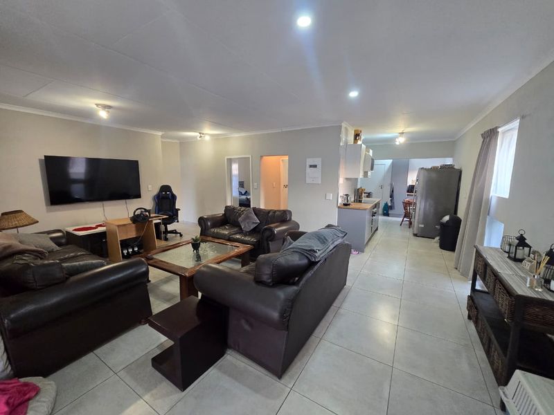 Spacious open-plan living area featuring tiled flooring, recessed lighting, and a functional kitchen layout, creating a versatile space for relaxation and dining.