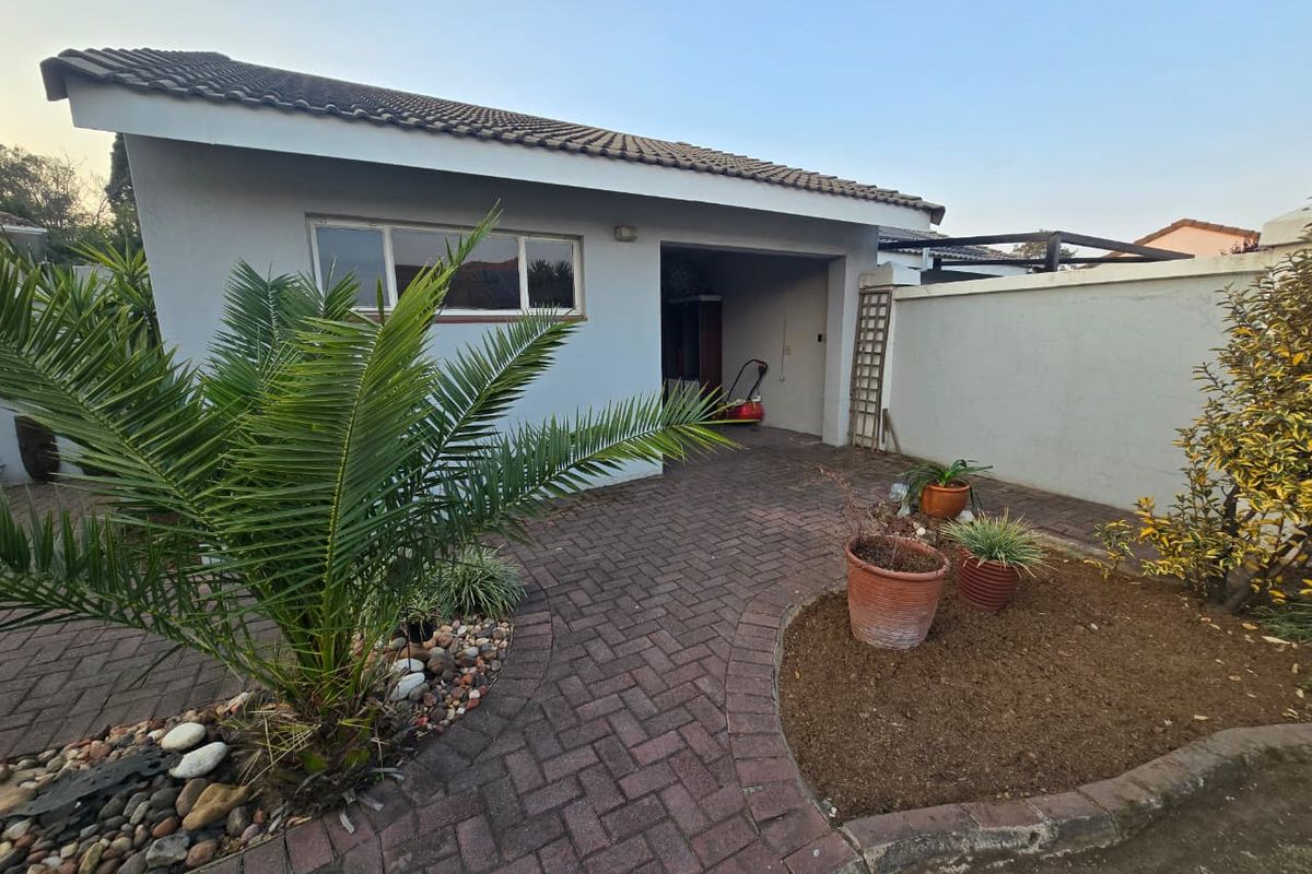 Rear exterior view of the townhouse featuring a paved courtyard area, boundary wall, and access to the garage.