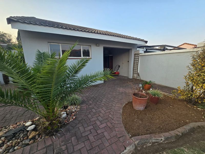 Rear exterior view of the townhouse featuring a paved courtyard area, boundary wall, and access to the garage.