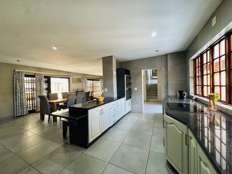 Spacious open-plan kitchen and dining area featuring granite countertops, built-in appliances, and neutral tiled flooring throughout.