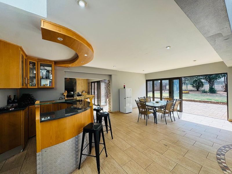 Spacious open-plan living area featuring a built-in bar with granite countertops, tiled flooring, and large sliding glass doors opening to the rear garden.
