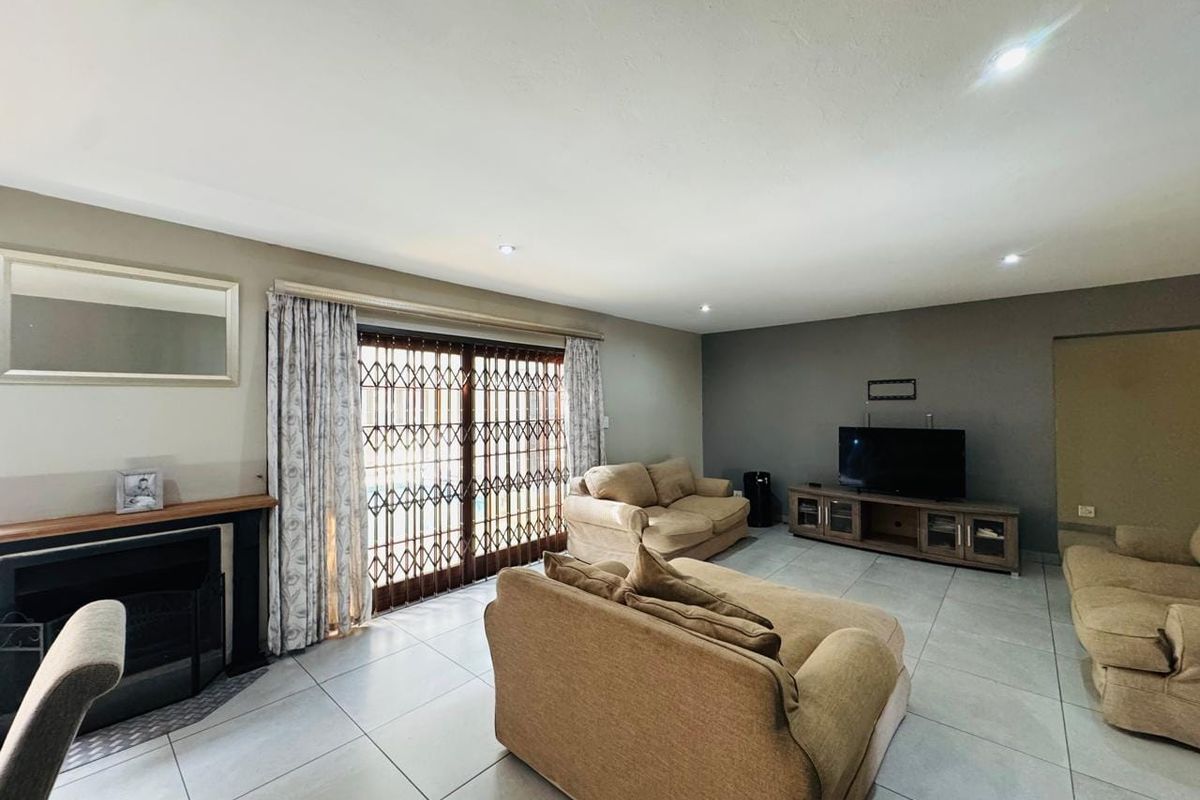 Spacious living room featuring tiled flooring, a fireplace, and a sliding glass door with security gate leading to the exterior.