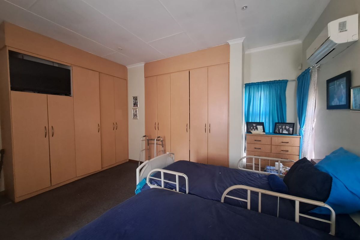 A bedroom featuring extensive built-in cabinetry for storage and a wall-mounted split-system air conditioning unit.
