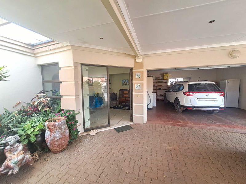 A covered patio area featuring paved flooring and a sliding glass door entrance, adjacent to an integrated garage space.